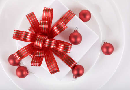 White present with red ribbons on a dinner plate, christmas themeの写真素材