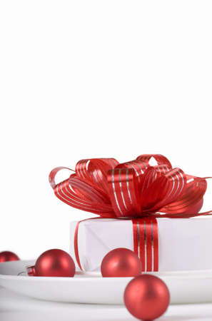 White present with red ribbons on a dinner plate, christmas themeの写真素材