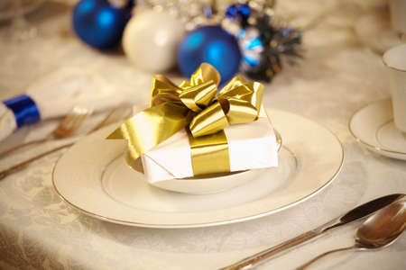 Elegant blue and white Christmas table setting with gold ribbon giftの写真素材