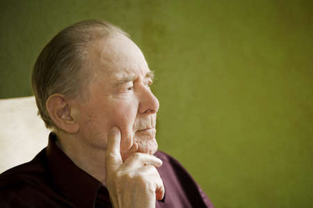 Elderly man in rocking chair looking out sunny windowの写真素材
