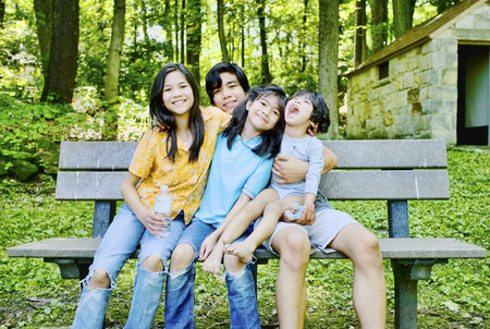 Four kids sitting on bench happy and hugging