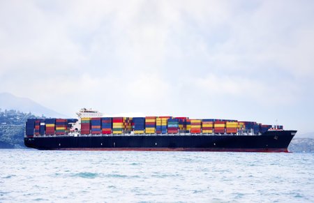 Large cargo ship in water carrying colorful shipping containersの写真素材