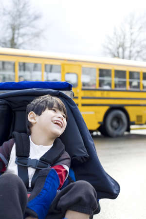 Disabled five year old boy in wheelchair, by schoolbusの写真素材
