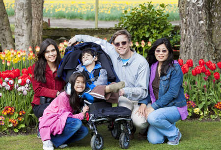 Interracial family in tulip gardens sitting near disabled boy in wheelchair の写真素材