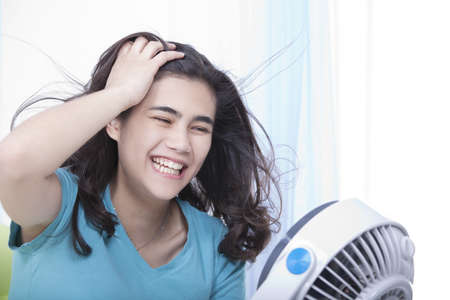 Beautiful young woman or teen enjoying cool fan breezeの写真素材