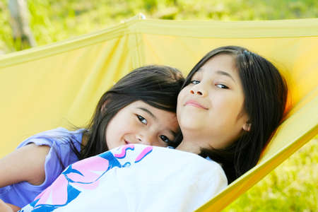 Two girls swinging on a hammockの写真素材