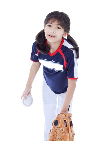 Little biracial asian girl in softball team uniform ready to throw a pitchの写真素材