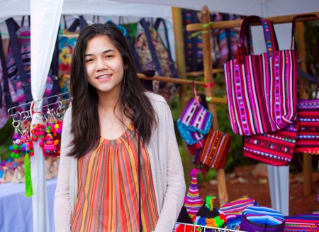 Biracial teen girl shopping at outdoor bazaar market in Thailandの写真素材