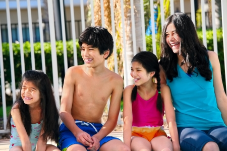 Four children, siblings,  enjoying the pool togetherの写真素材