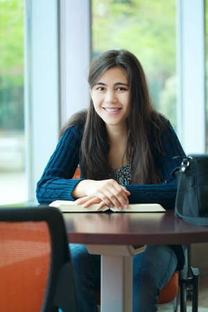 Happy young college student studying at school, book on tableの写真素材