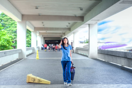 Young teen girl walking  along outdoor airport terminal with suitcaseの写真素材