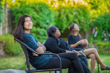 Friends sitting on lawn chairs outdoors talking in summerの写真素材