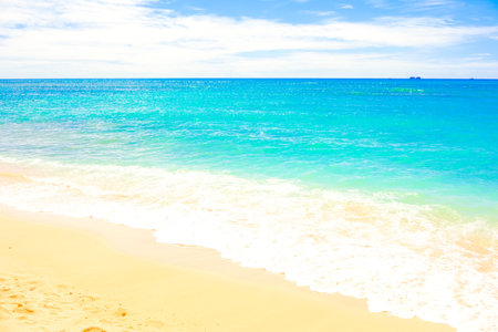 Beautiful clear blue aqua ocean waves with seafoam on warm sandy beach