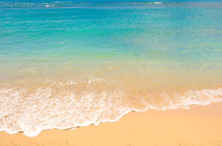 Beautiful clear blue aqua ocean waves with seafoam on warm sandy beachの写真素材