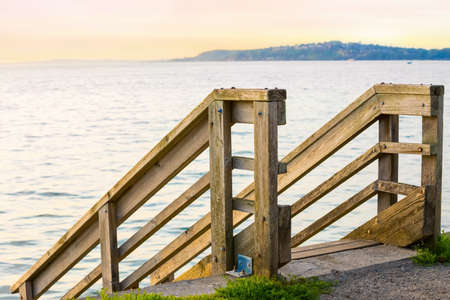 Wooden stair rails leading down to water in Pacific Northwest at sunset in summerの写真素材