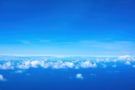 Line of fluffy white clouds just below horizon over blue oceanの写真素材