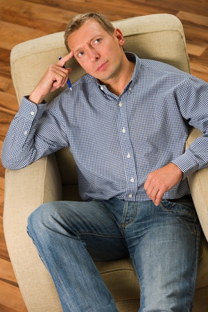 Man sitting on the armchair and thinking something.の写真素材