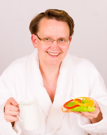 Woman start her day with a cup of coffee and the bread with a vegetables.の写真素材