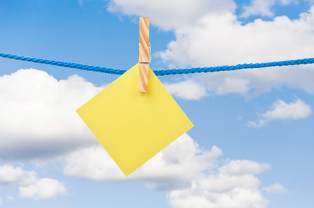 Yellow note hanging in a rope with sky background 