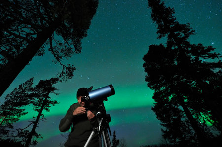 One night man watching northern sky, aurora behind.