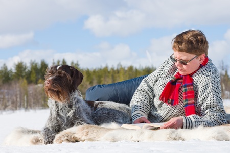 Woman laying down on the reindeer skin and reading the book.の写真素材
