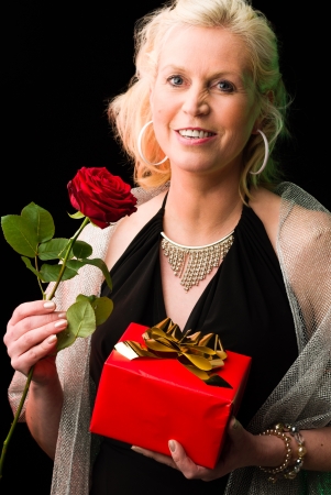 Partying woman with a rose and gift, black backgroundの写真素材