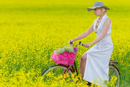 Woman stops front of rapeseed with a bicycleの写真素材