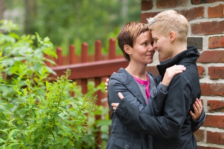 Two girls hugging front of fence and they look each other, horizon formatの写真素材