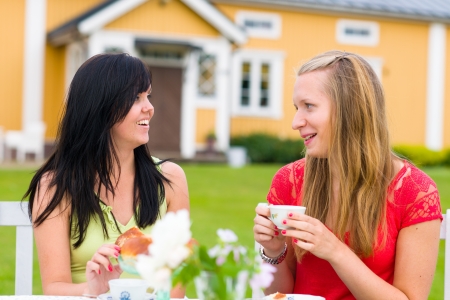 Two girl friends have a good time together on coffee tableの写真素材