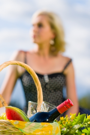 Picnic basket and woman out of the focus on background, vertical formatの写真素材