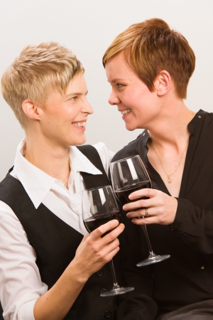 Two happy lesbians and a glass of red wine, vertical formatの写真素材