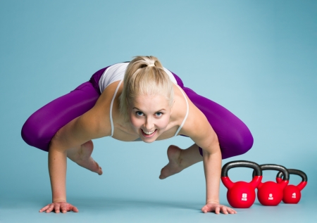 Fitness girl makes tricks, the kettlebells on backgroundの写真素材