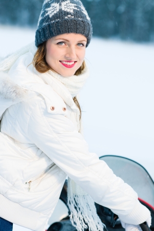 Winter, beautiful woman and a snowmobile, vertical formatの写真素材