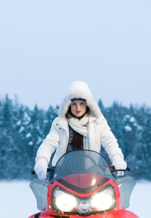 Winter, beautiful woman and a snowmobile, vertical formatの写真素材