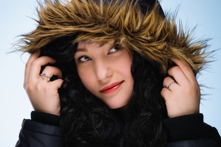 Beautiful girl wearing hood, light blue background, horizon formatの写真素材