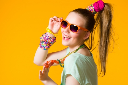 Smiling girl with colorful clothes wearing sunglasses, yellow backgroundの写真素材