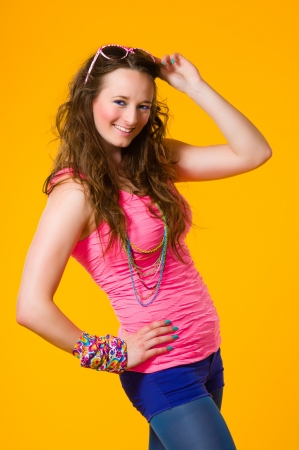 Beautiful girl wearing sunglasses, colorful clothes, yellow backgroundの写真素材