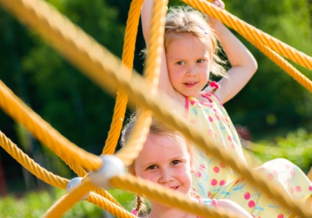 Two young girls on the jungle gym, sunny dayの写真素材
