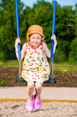 Smiling young girl on the swing, sunny dayの写真素材
