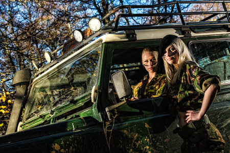 Beautiful girls on camouflage outfit, teamwork and off-road vehicleの写真素材