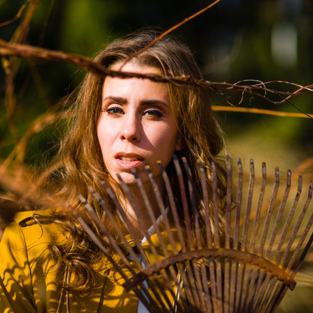 Beautiful fashionable woman and rake in the garden, springtimeの写真素材