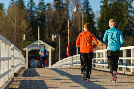 Two women jogging together along the bridge at sunriseの写真素材