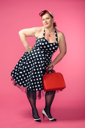 Mature pin-up woman wearing 50s style dress, pink backgroundの写真素材