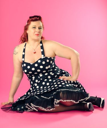 Mature pin-up woman wearing 50s style dress, pink backgroundの写真素材
