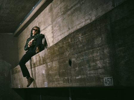 Young man wearing a sunglasses and he leans against a concrete wall - cross processed image, urban...