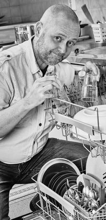Homeworks, smiling man to fill the dishwasher, black and white imageの写真素材