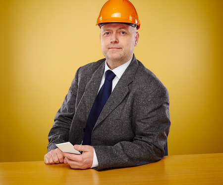Working male engineer in office, he wearing a white shirt and tie and coat, head he wears a orange hard hatの写真素材