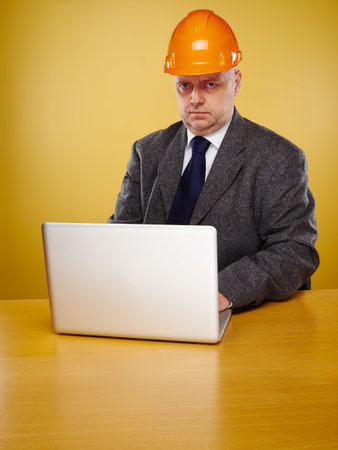 Working male engineer in office, he wearing a white shirt and tie and coat, head he wears a orange...