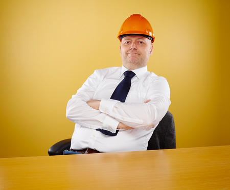 Male engineer in office, he wearing a white shirt and tie, head he wears a orange hard hatの写真素材