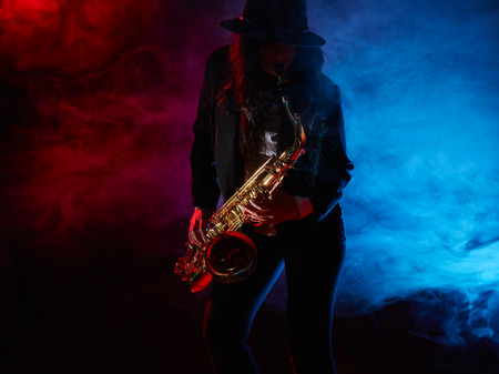 Saxophonist, beautiful young woman, smoky stage on backgroundの写真素材